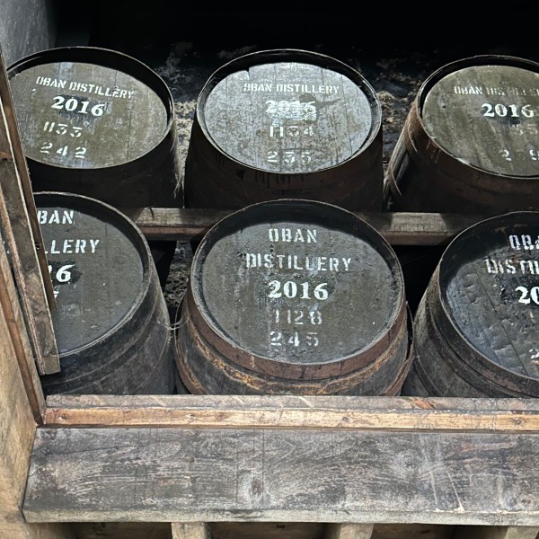 Wooden barrels labeled 'Oban Distillery 2016' in a storage area.