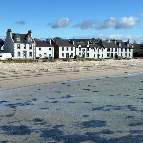 Row of white houses beside a beach under a clear blue sky.