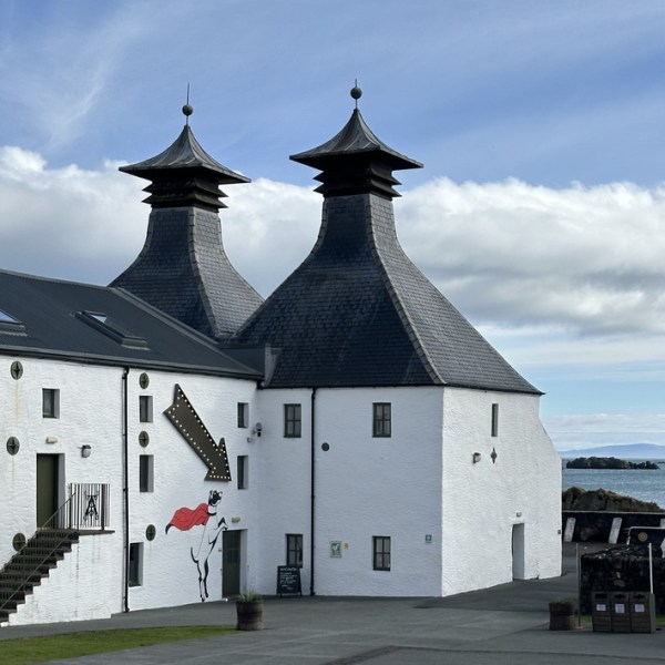 White building with two pagoda-style roofs, mural of horse, arrow, and sea in background.