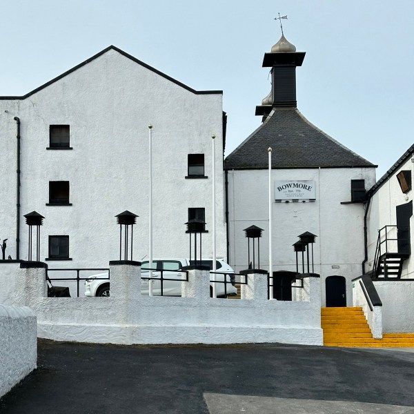 White building with Bowmore sign, black roof, and yellow steps.