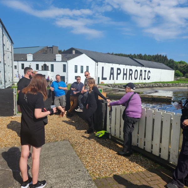 People gathered outside Laphroaig distillery with a clear blue sky.