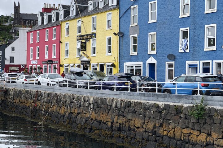 Colorful buildings by waterfront with cars parked in front on a cloudy day.