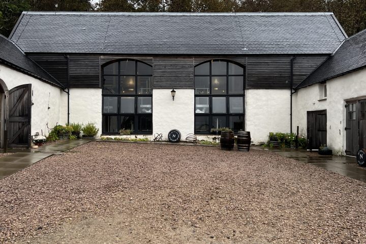 Courtyard with gravel, surrounded by buildings with large arched windows and slate roofs.