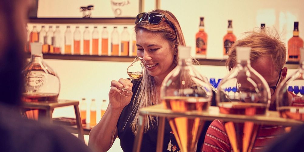 Woman smiling while smelling whiskey in a glass at a tasting event.